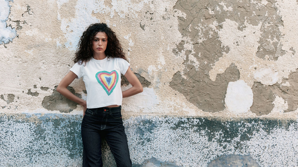 Woman wearing the 'Give With Heart' cotton t-shirt with heart graphic print, semi-cropped fit.